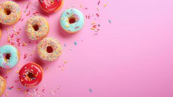 Colorful donuts with sprinkles on pink background, top view photo