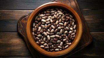 Top view of assorted beans in a wooden bowl on a wooden table photo