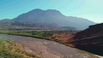 aereo Visualizza fuco volante al di sopra di panoramico roccioso montagne e un' rosso fiume paesaggio con un' chiaro blu cielo. quebrada de las concha, cafayate, salta, argentina. video