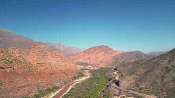 Aerial view drone flying over scenic rocky mountains and a red river landscape with a clear blue sky. Quebrada de las conchas, Cafayate, Salta, Argentina. video