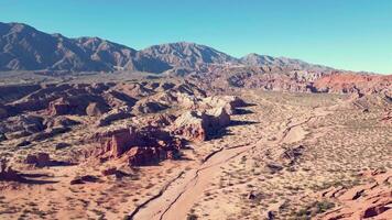 aereo Visualizza fuco volante al di sopra di panoramico rosso roccioso montagne e arido deserto paesaggio con un' chiaro blu cielo. video