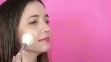 Woman applying make up on pink background video