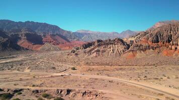 aéreo ver zumbido volador terminado escénico rojo rocoso montañas paisaje con un claro azul cielo. video