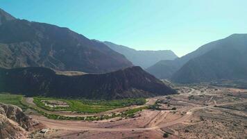 Antenne Aussicht Drohne fliegend Über szenisch felsig Berge und ein rot Fluss Landschaft mit ein klar Blau Himmel. Quebrada de las Conchas, Cafayate, Salta, Argentinien. video