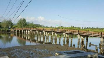 Wooden bridge over the river with blue sky background in Lombok, Indonesia. photo