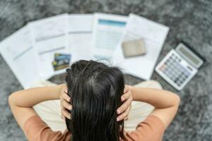 mujer estresada y con dolor de cabeza con grandes facturas o facturas sin dinero para pagar los gastos y la deuda de la tarjeta de crédito. escasez, problema financiero, quiebra, hipoteca, préstamo, en quiebra, pobre, billetera vacía foto