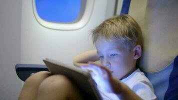 Bored or tired boy in plane using tablet computer video