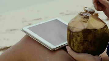 Woman using touch pad and having coconut drink video
