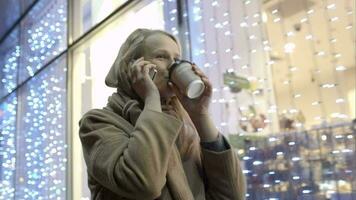 Woman talking on phone and drinking coffee while walking in street video