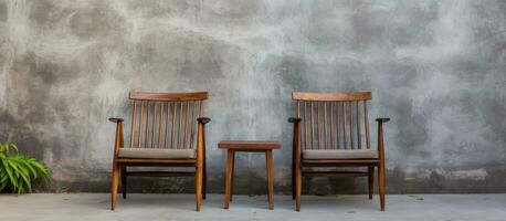 On a cement porch in front of the house there are two old wooden chairs and a polished cement wall photo