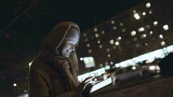 Woman with touch pad typing on her way in night city video