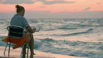 vrouw met stootkussen zittend Aan stoel door ruw zee video