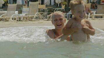 Mother and son jumping with waves in sea video