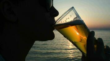 donna potabile birra su spiaggia a tramonto video