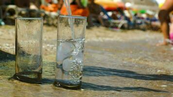 scrosciante acqua in Due bicchieri su spiaggia video