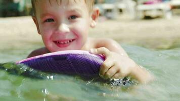 Little boy swimming on board near the shore video