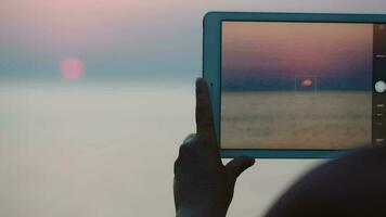 Taking pictures of sunset over sea with touch pad video