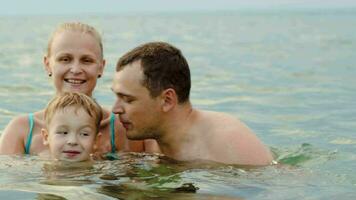 adorável família com criança tomando banho dentro mar video