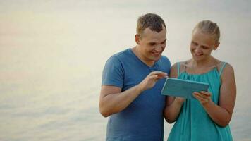 jovem casal usando tábua computador de a mar video