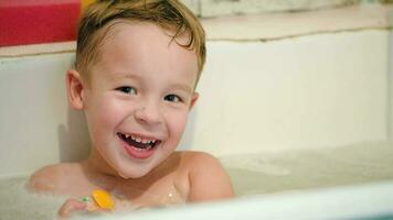 Lycklig liten pojke i bad med leksaker video