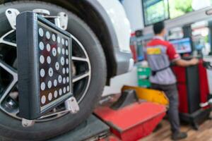 Car wheel balancer calibrate with laser reflector attach on each tire to center driving adjust. Balancing tire wheel machine at car repair service center. photo