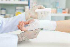 de cerca mano vestir médico guantes de médico mano atadura vendaje en el mano de paciente en clínica, osteofitos y tacón, fascia foto