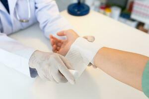 de cerca mano vestir médico guantes de médico mano atadura vendaje en el mano de paciente en clínica, osteofitos y tacón, fascia foto