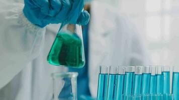 hand of scientist with test tube and flask in medical chemistry lab blue banner background video