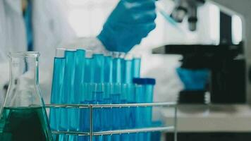 mano de científico con prueba tubo y matraz en médico química laboratorio azul bandera antecedentes video