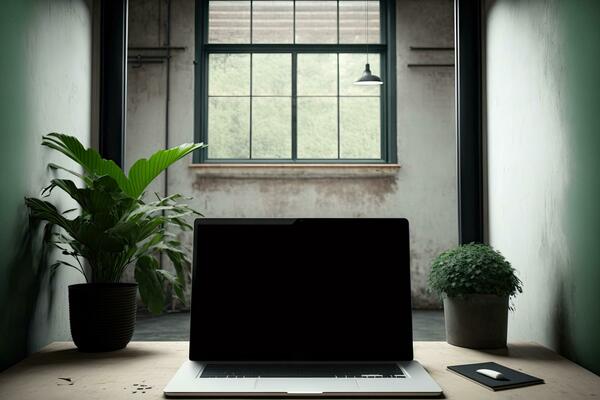 Interior of an industrial green ecological office loft with a laptop with a blank frameless screen mockup template on a table. Front view
