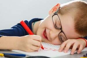 retrato de linda chico con bosquejo bolígrafo y papel a escritorio en salón de clases foto