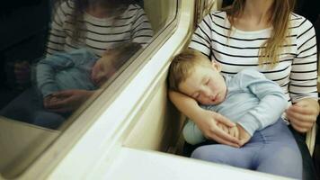 fatigué femme dans le train avec en train de dormir fils sur sa tour video