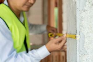 inspector o ingeniero es inspeccionando construcción y calidad garantía cheque dimensión de casa por utilizando un cinta medición. ingenieros o arquitectos o contactor trabajo a construir el casa antes de vender. foto