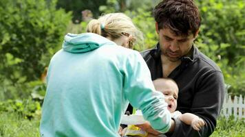 Young parents feeding a baby boy outdoor video