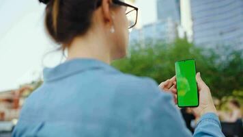 mujer es en pie en el calle y utilizando teléfono inteligente con verde pantalla video