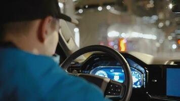 hombre conducción coche mediante el calles de noche ciudad. video