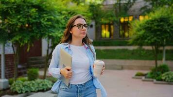 Woman walking on street with laptop and coffee in hands after work day video