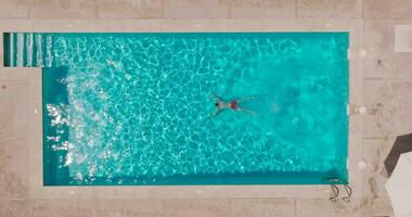 aéreo Visão Como uma homem mergulhos para dentro a piscina e nada, lento movimento video