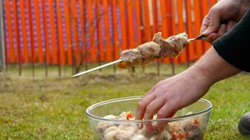 Man stringing marinated meat on a skewer video