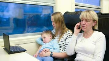 viaggiatori nel il treno Guardando video su il computer portatile e parlando Telefono