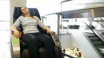 Woman having a rest in massage chair shopping center video