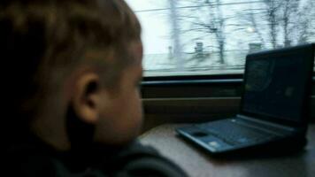 chico acecho película o dibujos animados en ordenador portátil en el tren video