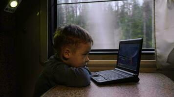 pequeño chico en el tren acecho vídeo en ordenador portátil video