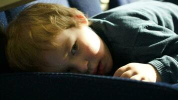 Little boy lying on the seat in bus, car ot train video