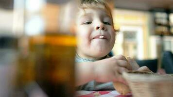 Cute boy eating a bun in cafe video