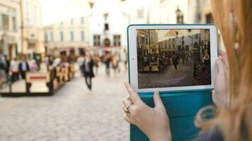 Woman with tablet making video of street in Tallin and then watching it