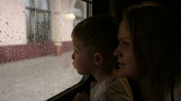 mãe e filho dentro trem olhando Fora a janela em uma chuvoso dia video