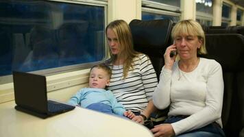 Son with mother watching video on laptop, grandma talking phone