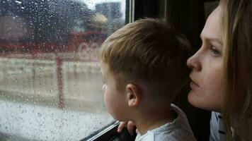 Boy and his mother looking out the window of train while it's rainy video