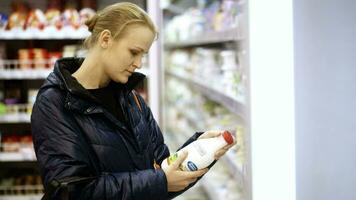 donna mettendo un' bottiglia di latte nel sua shopping cestino video